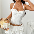 71686French-style, pure and elegant white embroidered halter top with a fitted waist, ruffled hem, and a fishbone-patterned back